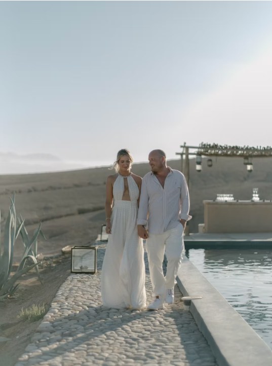 Agafay desert camp couple pool walk Couple walking along the pool of a desert camp in Agafay, Morocco