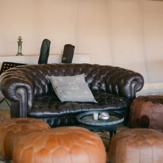 Leather sofa and Moroccan poufs inside a lounge tent in the Agafay desert