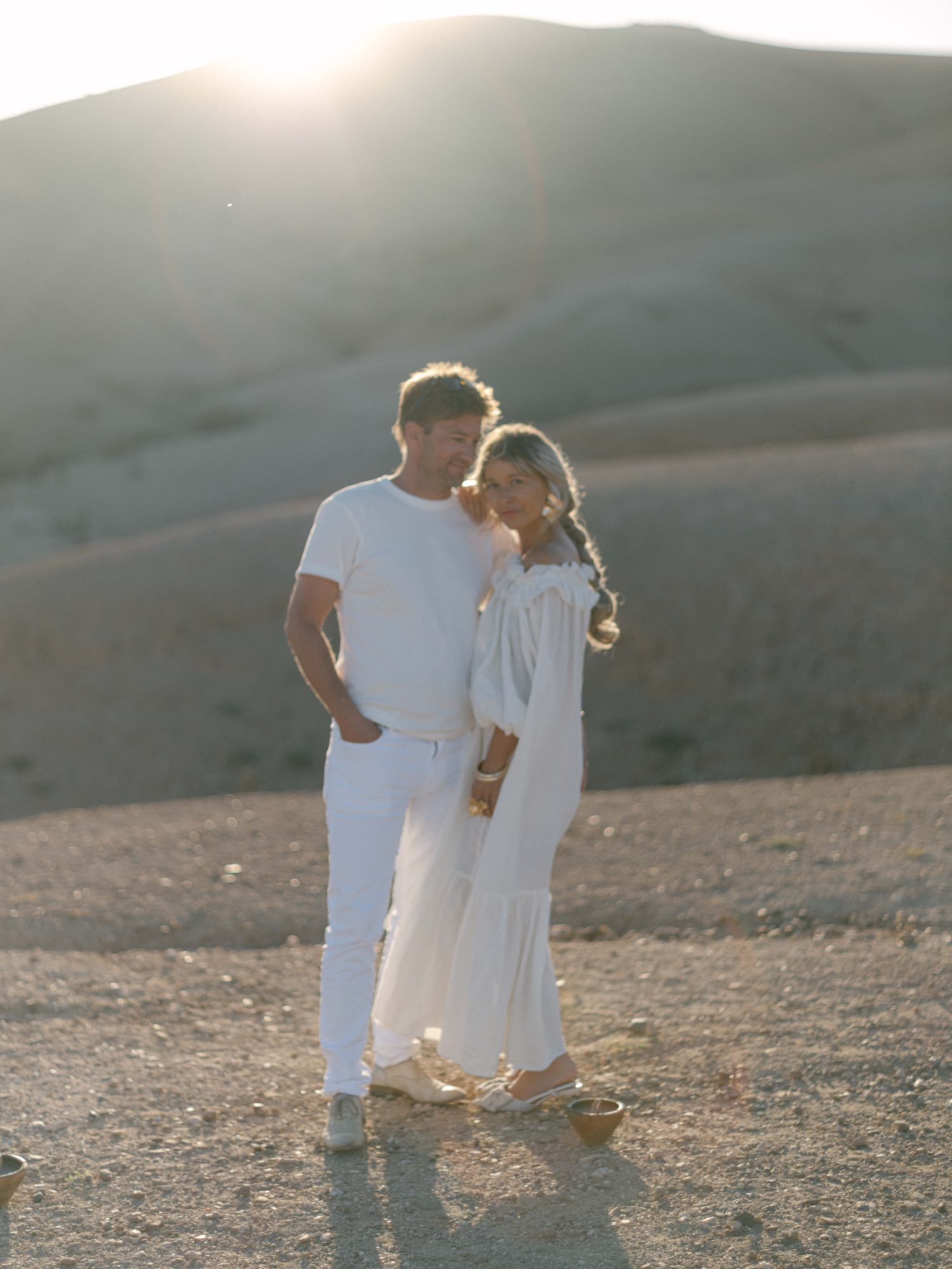 Agafay desert couple sunset backlight Couple dressed in white embracing at sunset in the Agafay desert hills