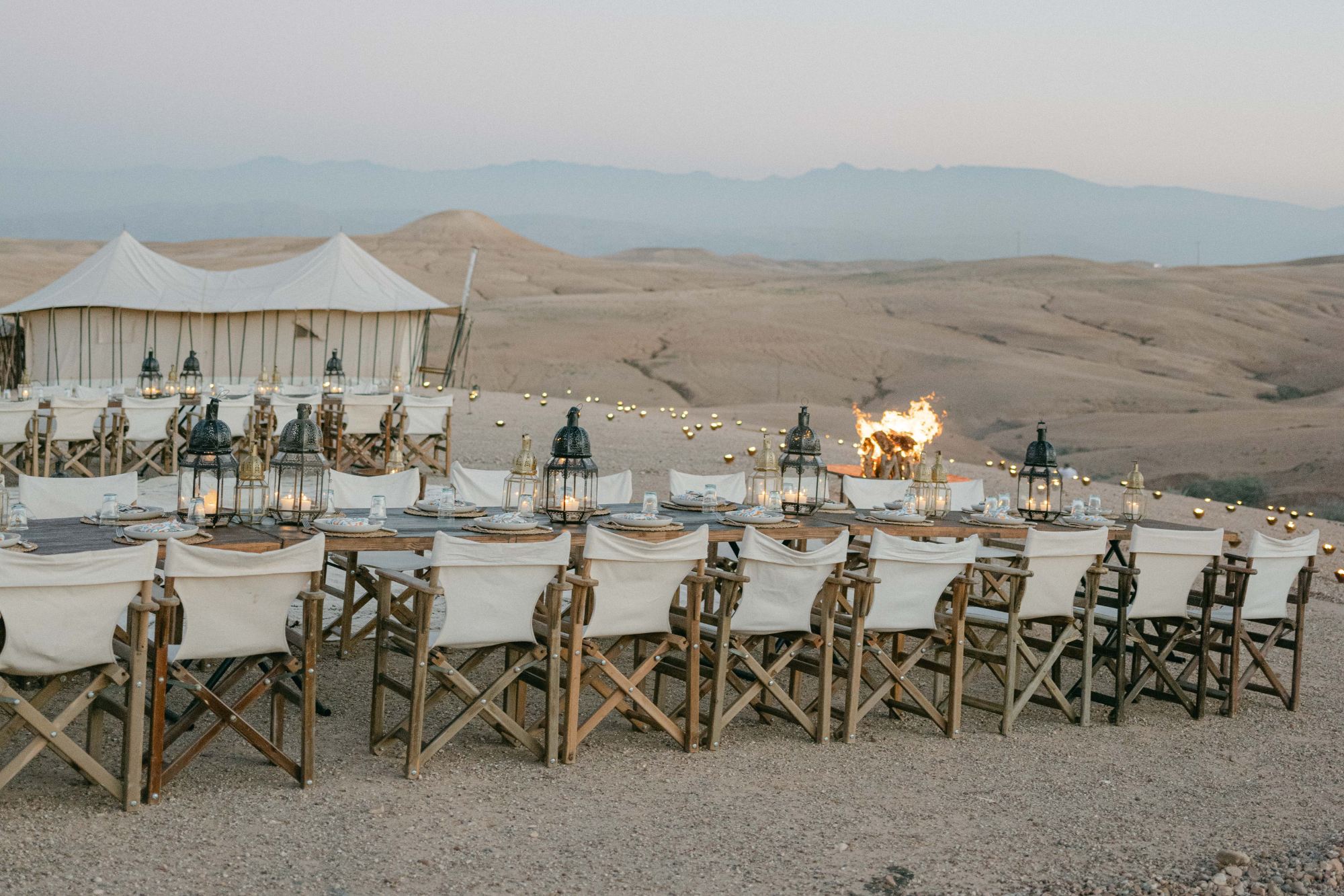 Agafay desert long dinner table tent wide Long dinner table with Moroccan lanterns facing the Agafay desert mountains