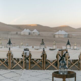 Moroccan rugs and a lantern table before dinner chairs and tents, Agafay desert