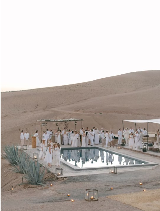 Agafay desert white party pool Guests dressed in white celebrating around a pool at an Agafay desert camp